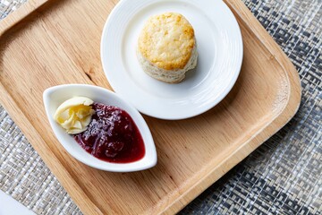 Scones and strawberry jam cups on wooden trays on tables at the café