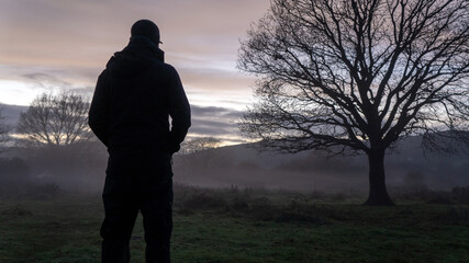 An atmospheric concept. Of a lonely figure, back to camera. standing in the countryside, looking at...