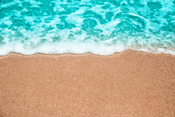 Fototapeta na wymiar Abstract summer background, Soft wave-covered sand beach with blue water.