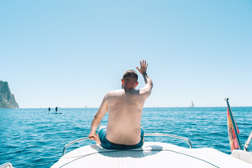 Young man sitting on boat deck at the mediterranean sea