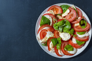 Italian caprese salad on a plate against a black background 