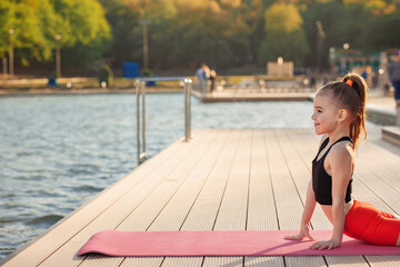 Beautiful young slim girl doing yoga or gymnastic exercise by the lake. Healthy lifestyle....