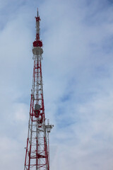Telecommunication tower with antennas on a background of blue sky with clouds