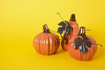 ceramic Halloween pumpkins with brown metal leaves on yellow background