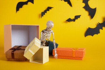 plastic skeleton and gift boxes on yellow background