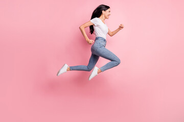 Full size profile photo of optimistic brunette lady jump run wear t-shirt jeans sneakers isolated...