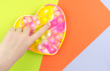 Bright colored toy Pop it fidget on a colored background. Children's toy for the development of fine motor skills.