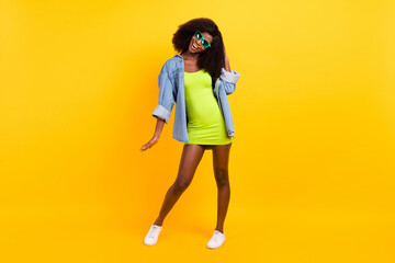 Full length body size photo of girl in green dress wearing sunglass dancing overjoyed isolated vibrant yellow color background