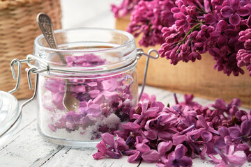 Fototapeta na wymiar Making lilac sugar. Lilac flowers and sugar in a preserving jar. Bunch of blossom Syringa on background.