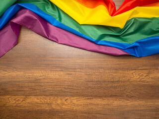 Rainbow flag (LGBT) laid on a wooden background. Top view. Flat lay. Space for text. Love concept