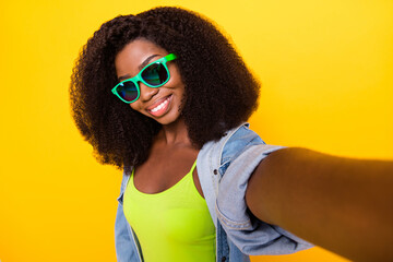 Photo of charming funky dark skin lady dressed denim outfit glasses recording video isolated yellow color background