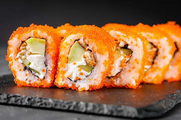 appetizing sushi roll california with eel cheese cucumber avocado and caviar masago on a black stone plate