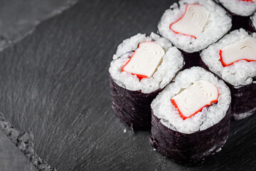 appetizing sushi roll maki with crab stick on a black stone plate © Narsil