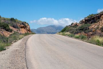 curving desert road upward, with views of the mountains and dramatic sky