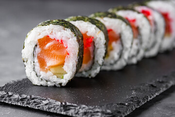 appetizing sushi roll maki with salmon on a black stone plate © Narsil