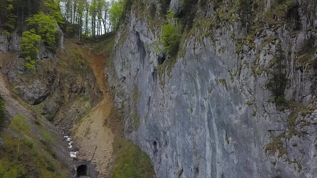 Aerial drone flight near a vertical stone wall and then above the rocky crest of Buila Mountains and Cheia Gorges. Stunning rocky canyon during early summer. Carpathia, Romania.