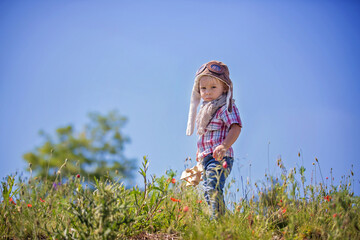 Beautiful toddler baby boy, child playing with airplane in poppy fiead, , sunny afternoon