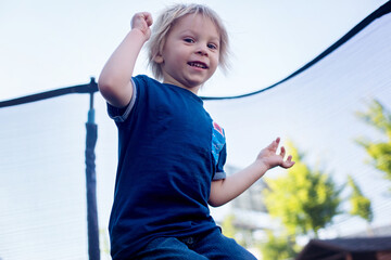 Cute little boy with static electricy hair, having his funny portrait taken outdoors on trampoline