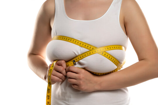 a woman measures with a measuring tape her large breasts