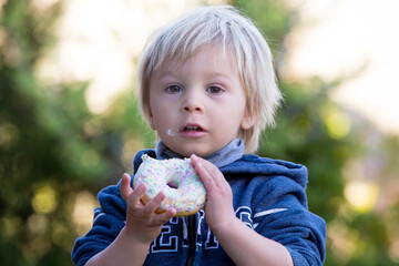 Cute child, eating donnuts in garden