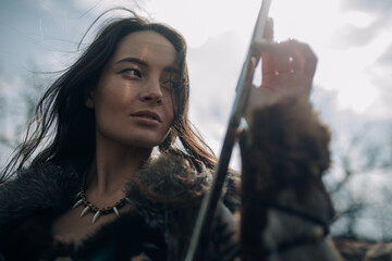 Portrait of woman in image of warrior amazon with sword in her hands.