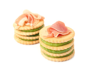 Delicious crackers with cucumber and prosciutto on white background