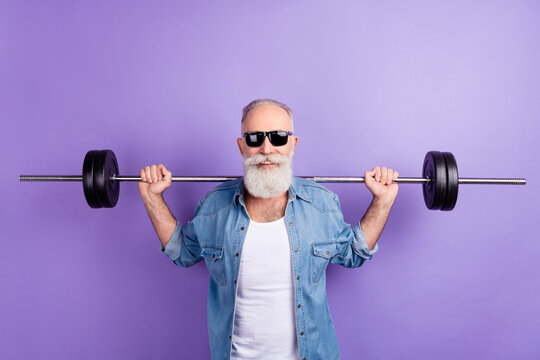 Photo of aged sporty man training intense muscles arms barbell isolated over violet color background