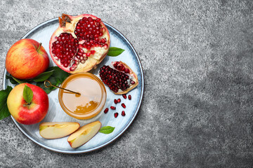 Fototapeta na wymiar Honey, pomegranate and apples on grey table, top view with space for text. Rosh Hashana holiday