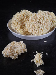 Ranginang or rangginang or rengginang is Indonesian traditional crispy rice or glutinous rice crackers, served in white plate against black background. Kind of deep fried food. 