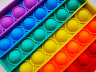 Anti-stress toy poppit. Push bubble toy. Rainbow colors. Close-up. Colored abstract background.