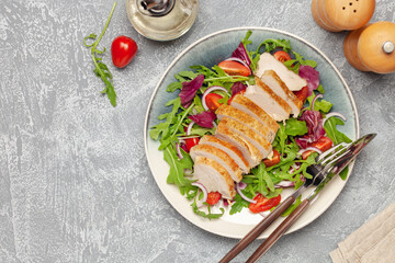 Chicken breast on the leaves arugula with radicchio, tomatoes and onions. Balanced lunch. Top view