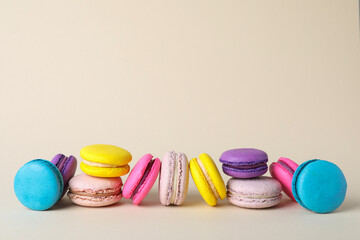 Delicious colorful macarons on beige background. Space for text
