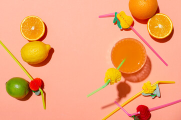 Top view of fresh lemons,lime,oranges and glass of fruit cocktail, staws on the brigt orange surface.Empty space