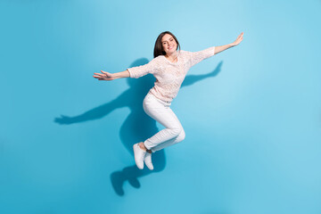 Fototapeta na wymiar Full body photo of cheerful happy young woman jump up air hold hands plane wings isolated on blue color background