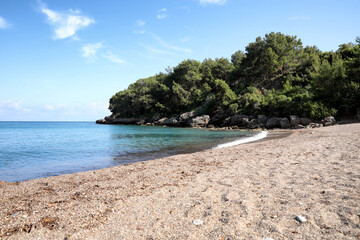 Beautiful sea beach near rocky hill with forest on sunny summer day