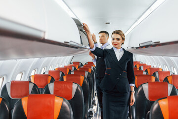 Young stewardess with steward on the work in the passanger airplane