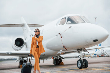Cloudy weather. Passenger woman that is in yellow clothes, sunglasses and with luggage