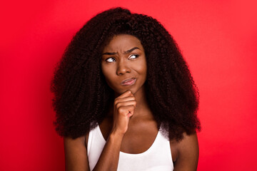Fototapeta na wymiar Photo of young african girl unhappy upset hand touch chin think look empty space isolated over red color background