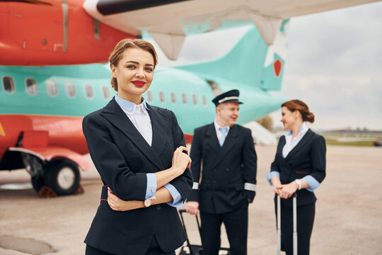 Aircraft crew in work uniform is together outdoors near plane