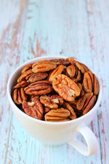 A Cup Filled with Pecan Nuts Isolated on Pale Blue Wooden Table