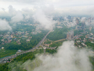 Fototapeta premium Motherland monument in Kiev between the clouds. Aerial drone view.