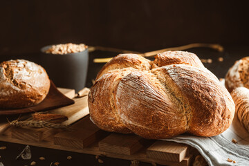 Bread on dark background. Fresh crispy baking, old style. - obrazy, fototapety, plakaty