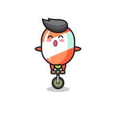 The cute candy character is riding a circus bike
