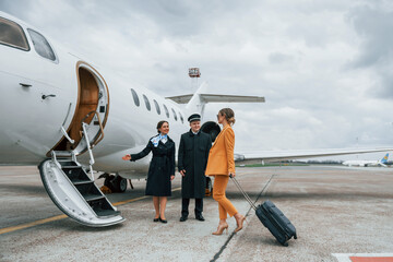 A young woman in yellow clothes is accompanied by an airline workers