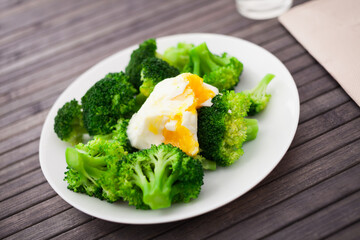 boiled broccoli inflorescences with boiled egg in plate