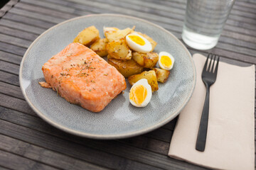 baked salmon fillet with fried potato wedges and quail eggs halves