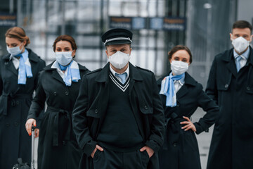Aircraft crew in work uniform is together outdoors in the airport