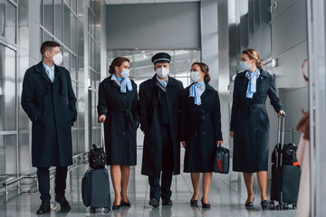 Aircraft crew in work uniform is together outdoors in the airport