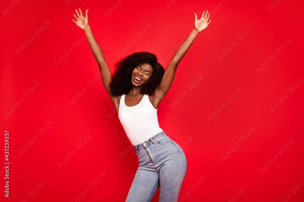 Wall mural Photo of young excited african girl happy positive smile have fun enjoy hands up music dance isolated over red color background