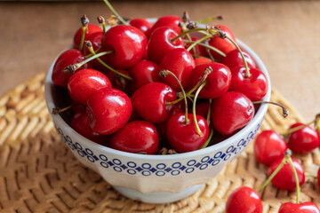 Cherries in a bowl, on a rustic wooden background.